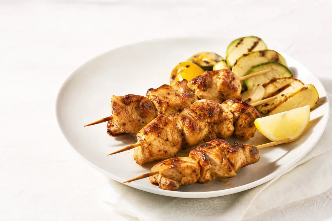 Brochettes de poulet marinées dorées et servies sur assiette avec légumes grillés